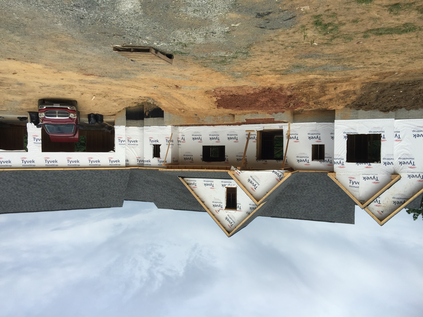 Large custom home under construction with roofing and weather barrier installed